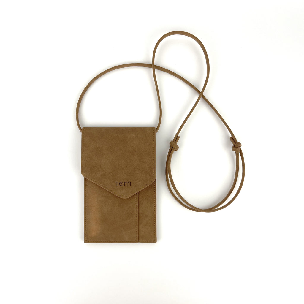 A suede brown plant-based leather phone bag with a magnetic flap closure and a matching adjustable neck strap, featuring the debossed brand name 'tern' on the front, shown on a plain white background.